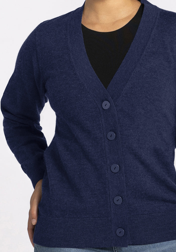Model in Woolx Gia Sweater - Ocean Cavern over black top and blue jeans, hand on hip, against white background.