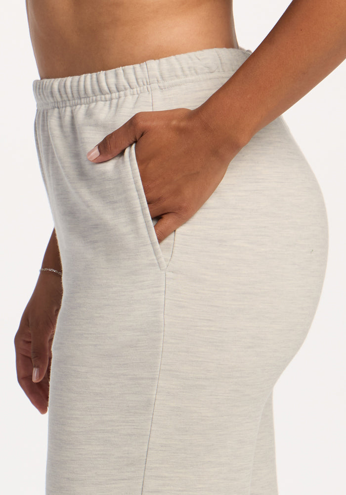 Someone in Woolx Juliette Joggers - Light Ash stands sideways, hand in pocket, against a white background.