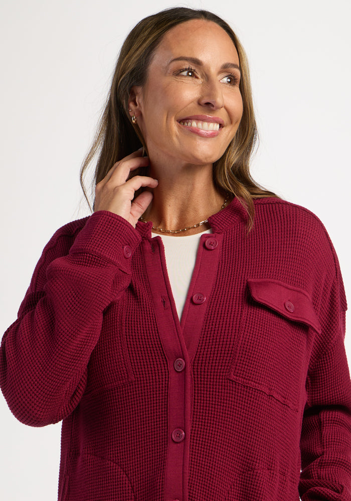 Woman smiling, wearing the Woolx Oaklynn Waffle Shacket in Beet Red over a white top against a plain background.