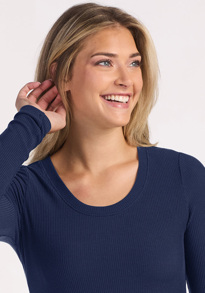 Smiling woman in Woolx Caroline Ribbed Twirl Dress - Ocean Cavern, holding her hand up near her ear.