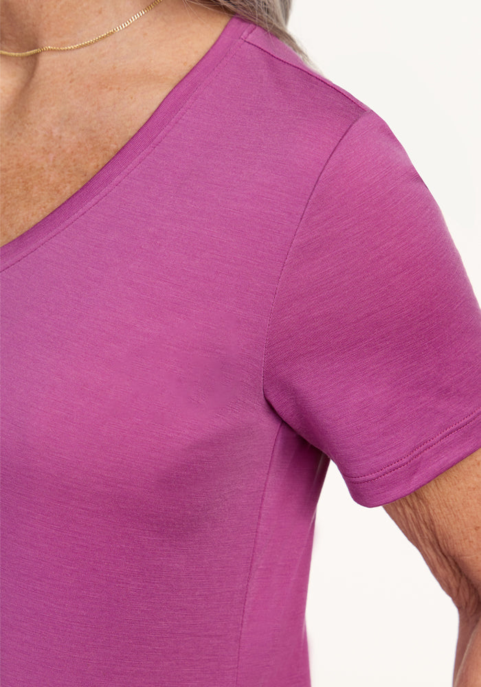 Close-up of a person wearing the Woolx Junie V Neck in Purple Wine, a women’s relaxed fit, short-sleeved Merino wool tee, paired with a thin gold necklace. The background is plain and light-colored.