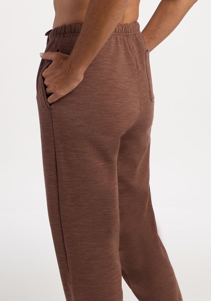 Model in Woolx Juliette Joggers - Sable Heather, side view, one hand in pocket; features moisture-wicking merino.