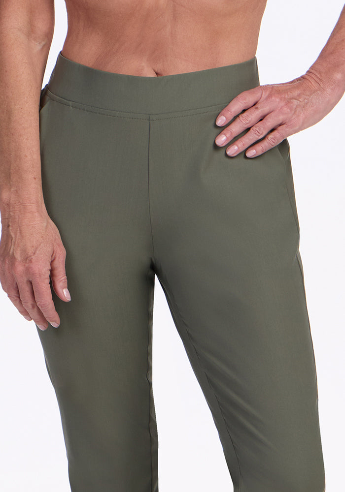 A person models the Woolx Nicole Ankle Pants in Sage Olive, standing against a plain light background with one hand on their hip and the other relaxed by their side.