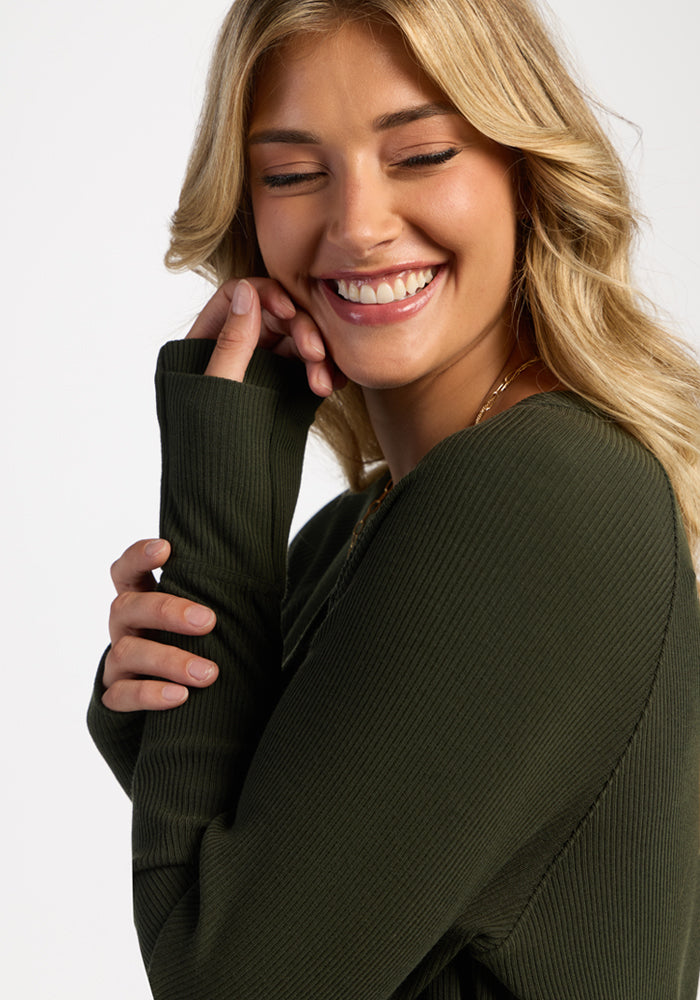 Smiling woman in Woolx Ainsley Sweater - Duffel Bag, ultra-soft Merino wool, eyes closed, wavy blonde hair.