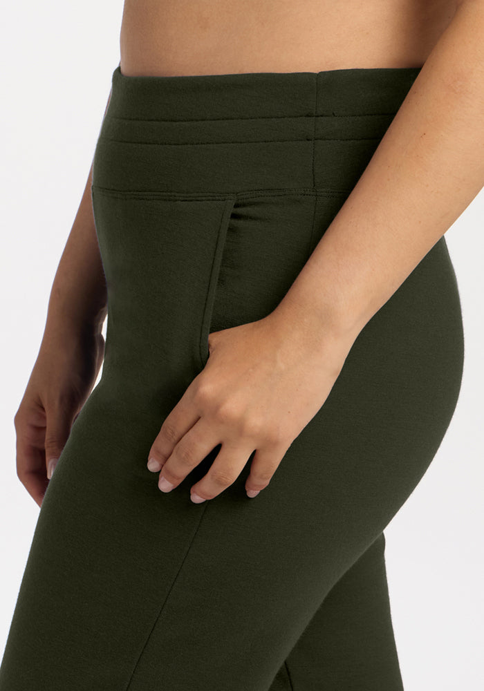 A close-up of a person wearing Woolx Willa Joggers in Duffel Bag, one hand resting by their side.