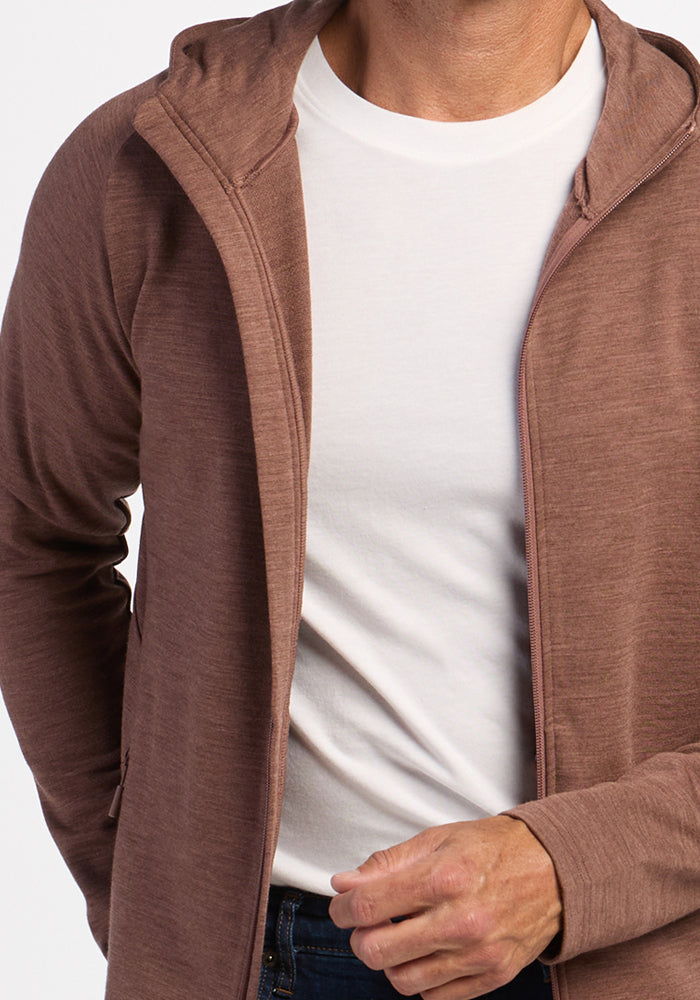 Man wearing Woolx Boulder Hoodie - Sable Heather over a white tee, hand partially visible near the zipper.