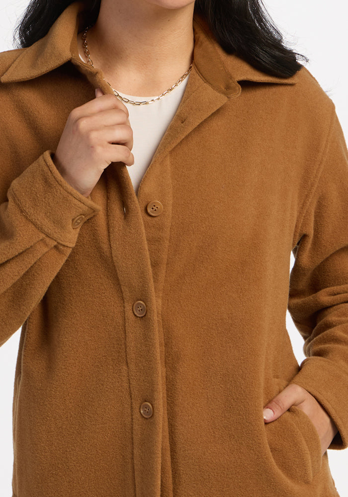 Person in a Woolx Jovie Shacket - Saddleback, one hand on the collar, styling it with a chain necklace.