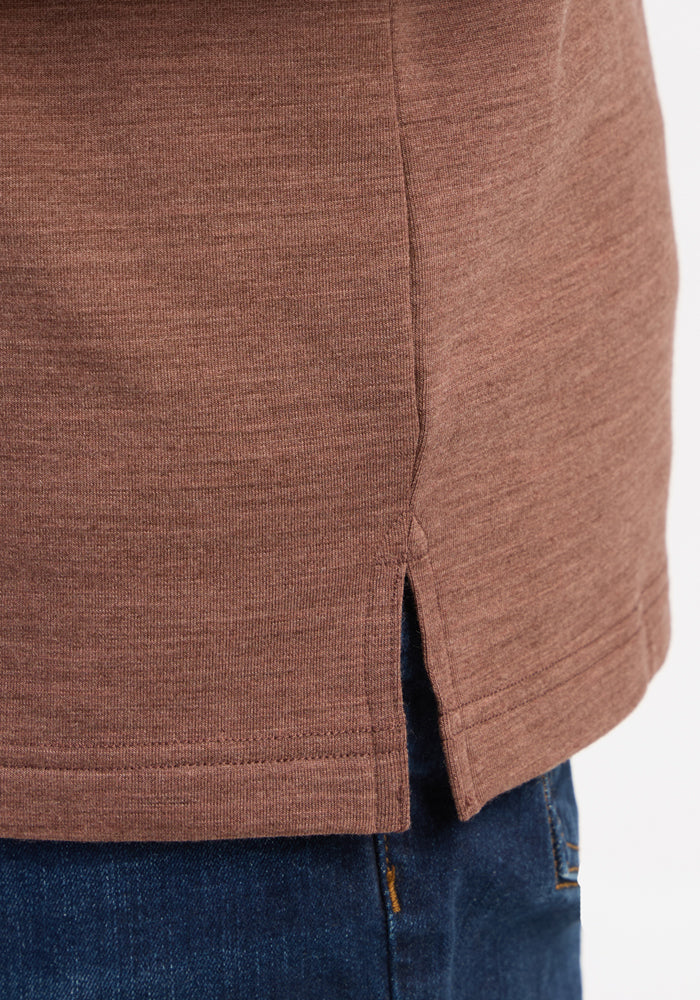Close-up of Woolx Jackson Henley - Sable Heather’s hem, featuring a side slit, worn over blue denim jeans.