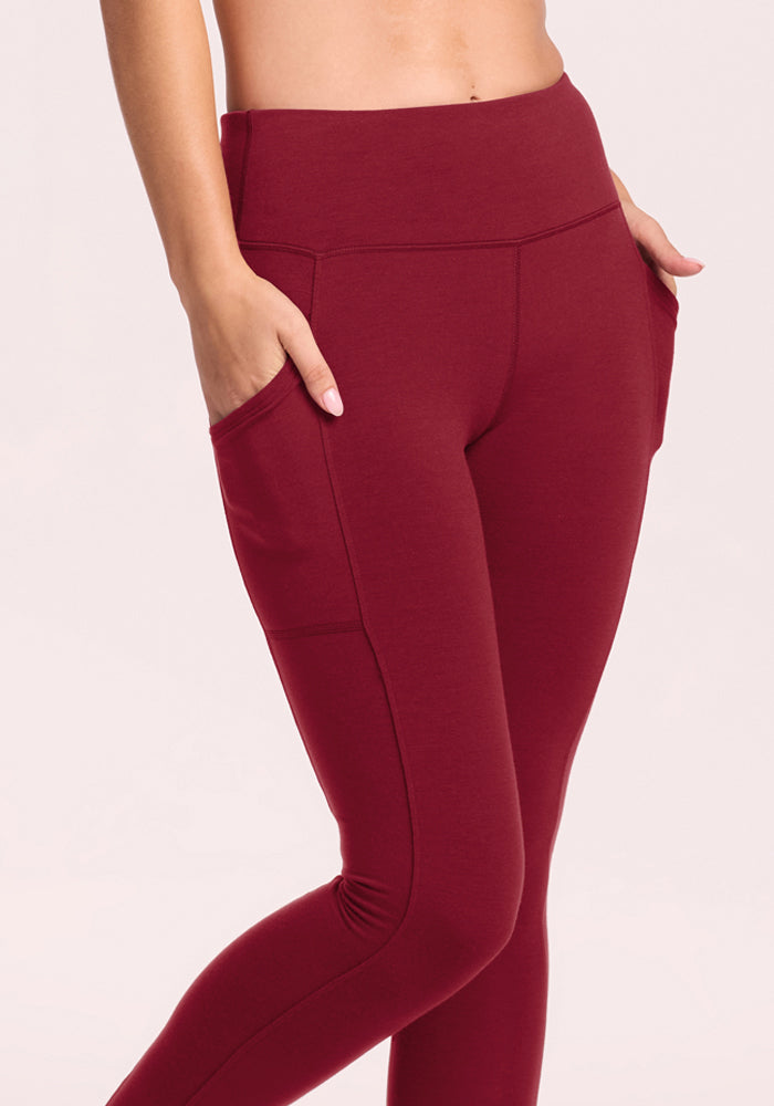 Model wears Woolx Piper Pocket Leggings in Pinot Noir, high-waisted with pockets; shown midriff to ankles.