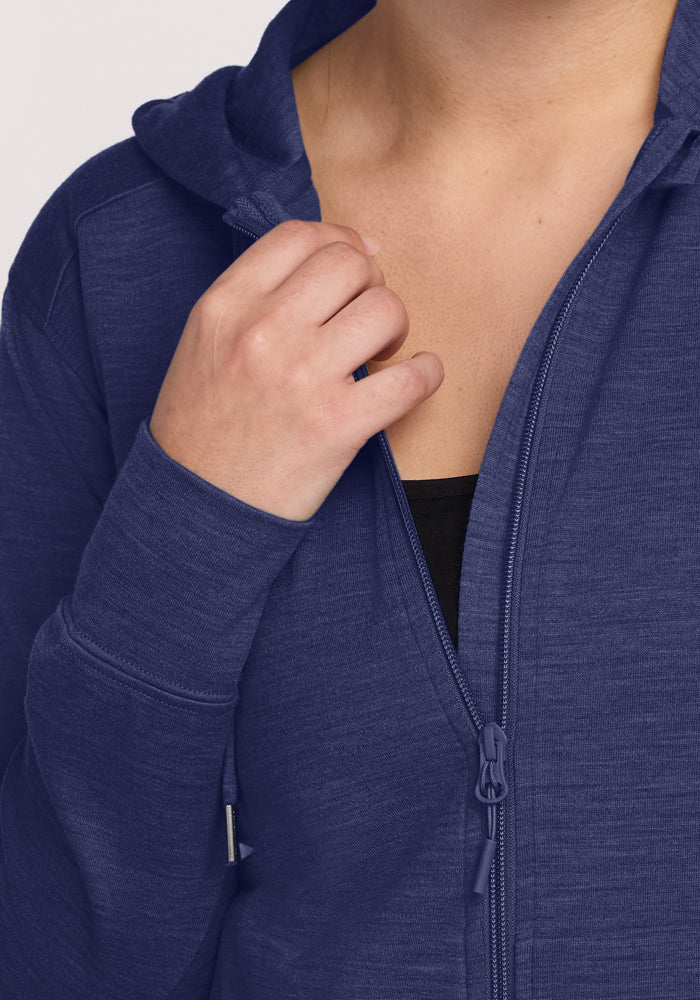 A hand zips up the Woolx Ryann Hoodie in Twilight Storm—lightweight, blue, and perfect for travel.