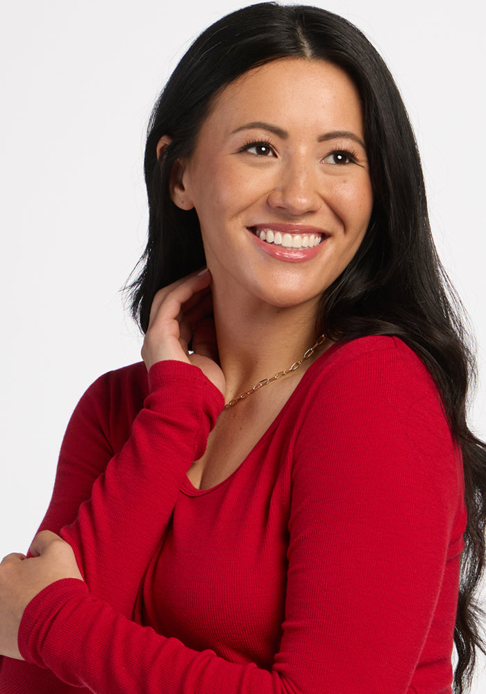 Woman with long dark hair wears the Woolx Katie Ribbed Long Sleeve in Maraschino Cherry, smiling to the side.