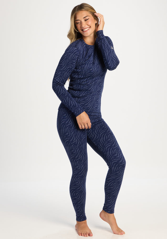Smiling woman in Woolx Maddie Baselayer Top - Midnight Safari, standing barefoot on white.