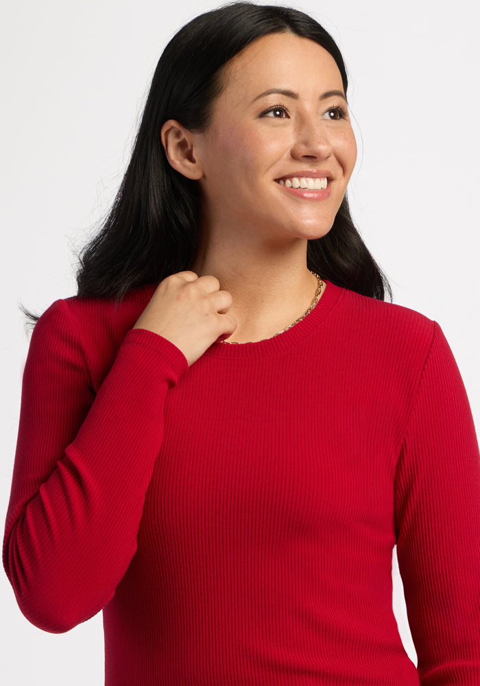 Woman with long dark hair smiles in the Woolx Hadley Ribbed Crew - Maraschino Cherry, against a white background.
