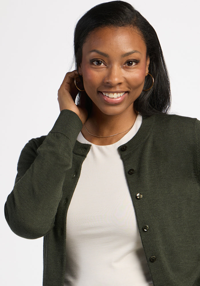Woman smiles in the Woolx Caitlin Sweater - Duffel Bag, over a white top, with gold hoops and a necklace.