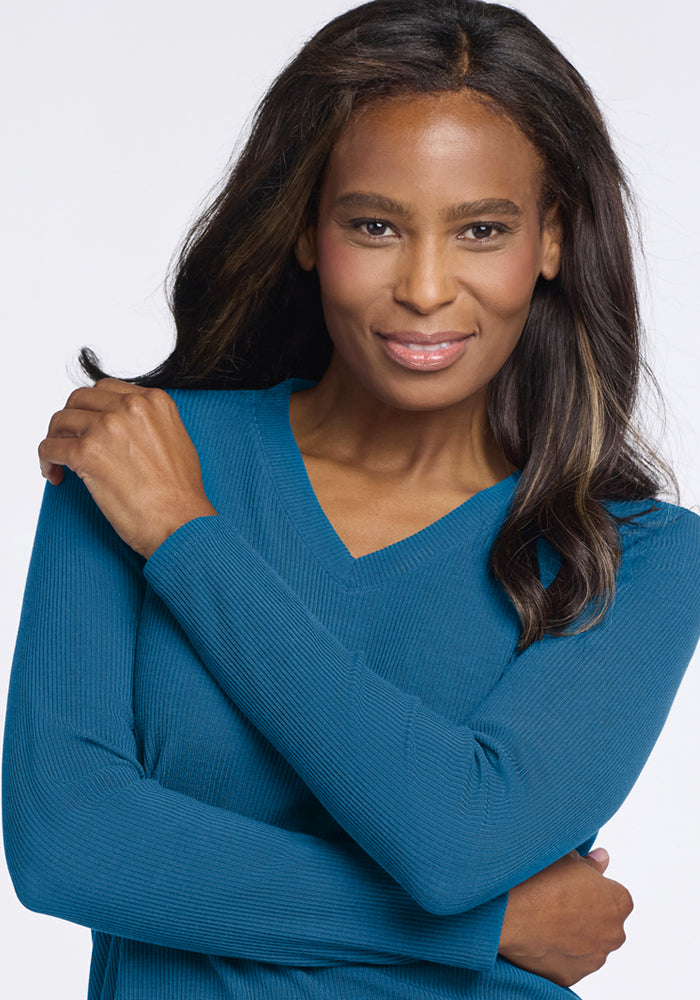 Smiling woman in the Woolx Evie Ribbed Tunic - Blue Pine stands with one arm crossed, hand on her shoulder.