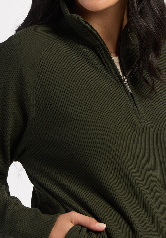 Woman in Woolx Quinn Ribbed 1/4 Zip - Duffel Bag, hand in pocket, face partially visible.