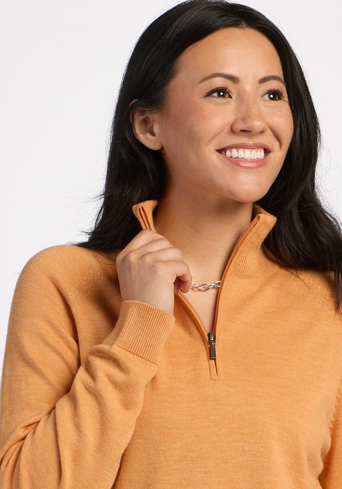 Woman in Woolx Collins Half Zip Sweater – Butterscotch, holding collar, with long dark hair and light background.