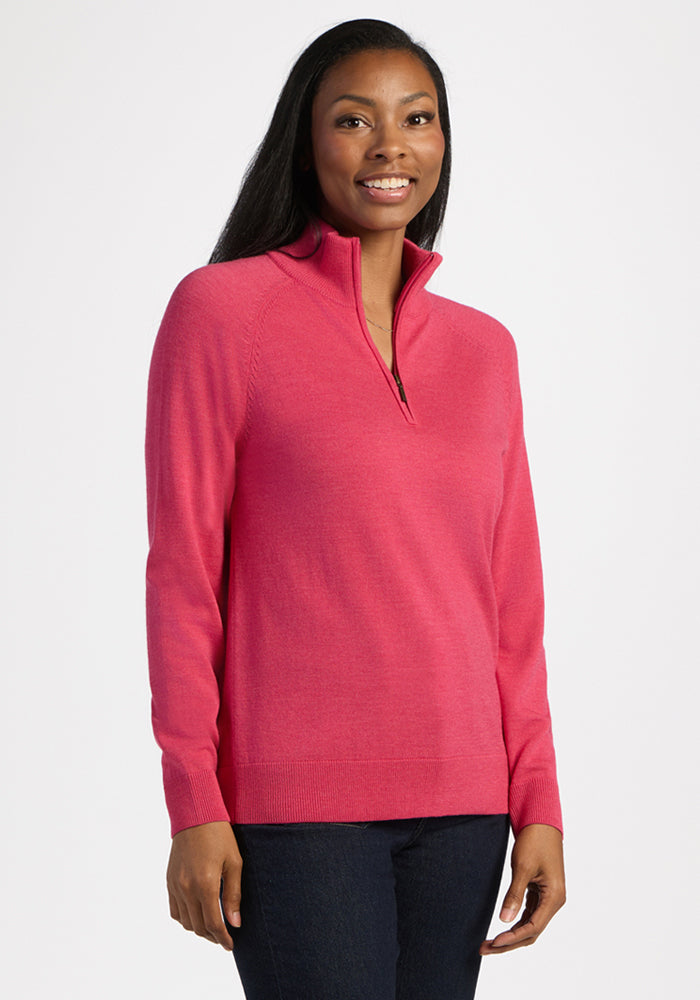 Woman in Woolx Collins Half Zip Sweater - Vivid Rose, smiling confidently in dark pants against a plain white background.