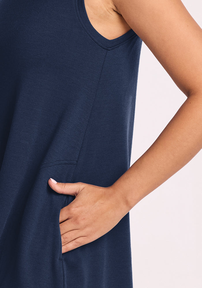 A person wearing the Woolx Clara Dress in Deep Navy stands against a light background, their right hand casually tucked into the side pocket with their arm bent at the elbow.