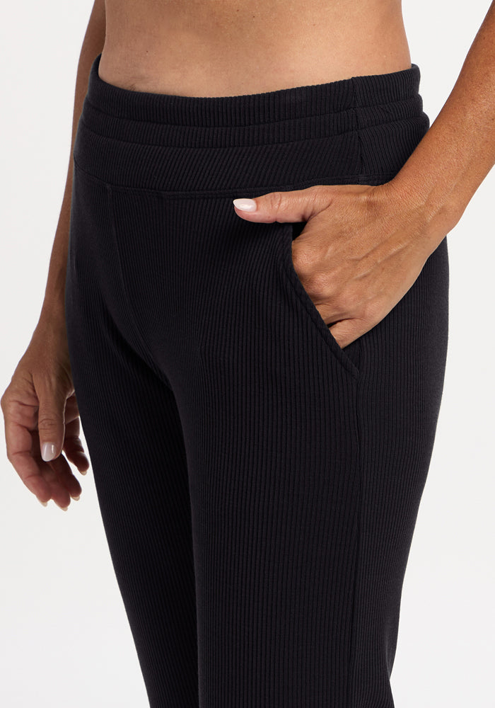 Model in Woolx Lennon Ribbed Joggers - Black, hand in pocket; waist to mid-thigh view highlights luxe ribbing.