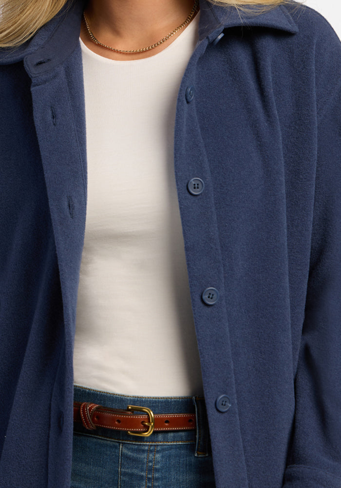 Woman in Woolx Jovie Shacket - Deep Dive, white shirt, brown belt, jeans & gold necklace—ideal cozy layering.