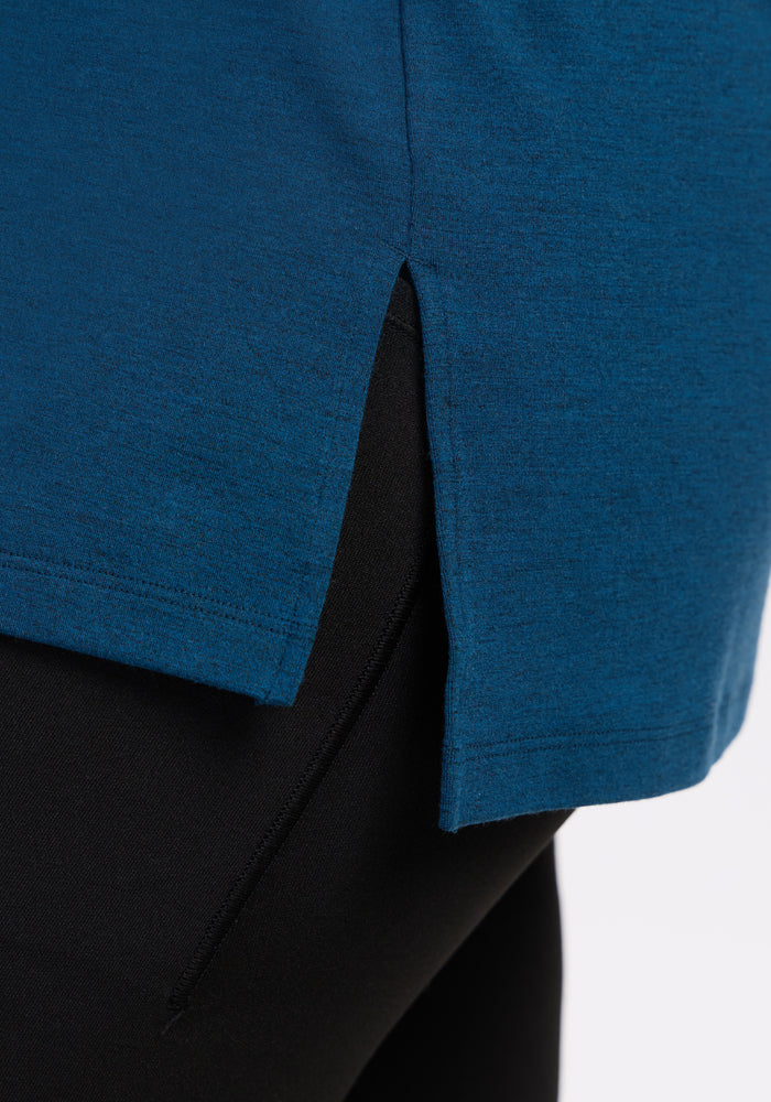 Close-up of the Woolx Audrey Tee in Majolica Blue, showing its lightweight design, side slit, and hem detail as worn over black pants. This comfortable tee features a small vertical opening on the side.