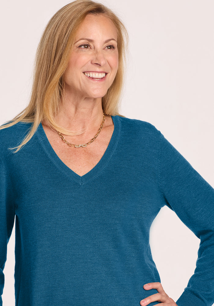 Smiling woman with long blonde hair in Woolx Francesca Sweater - Blue Pine, wearing a gold chain necklace.