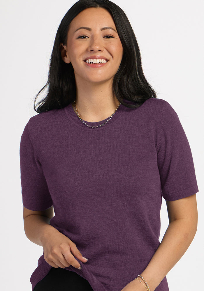 Woman with long dark hair wears Woolx Anna Crew Sweater in Purple Iris and a gold necklace against a white background.