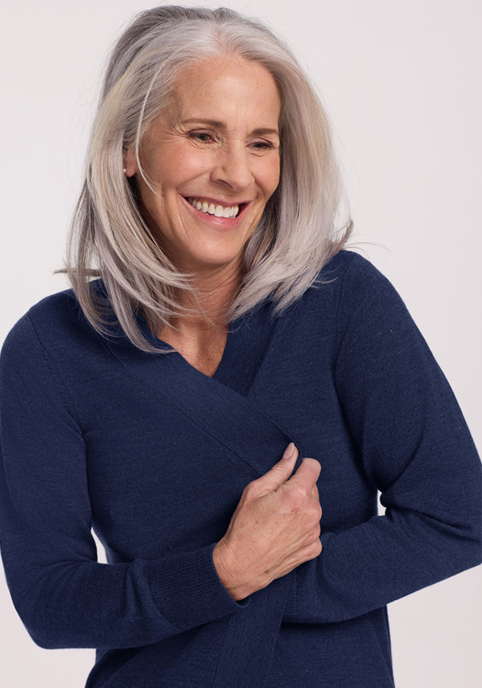 Smiling older woman with gray hair in the Woolx Macie Sweater - Ocean Cavern, arm across her chest.