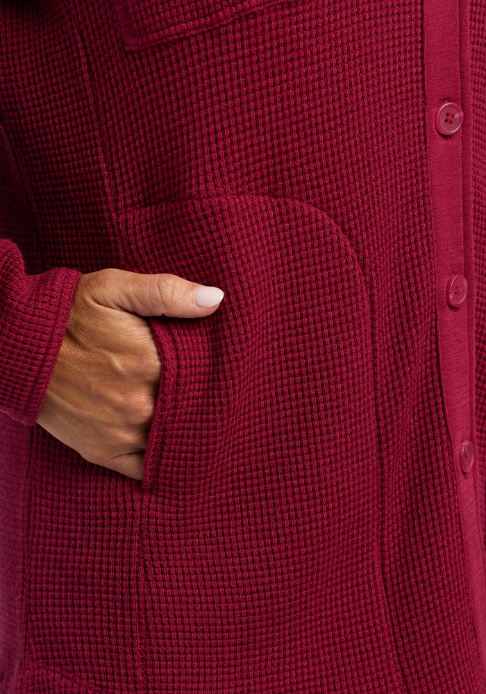 A hand with light skin is placed in the pocket of a Woolx Oaklynn Waffle Shacket in Beet Red.