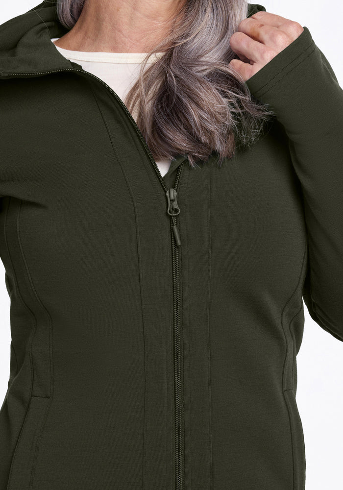 Woman with wavy gray hair wears a Woolx Zoey Zip Up Hoodie in Duffel Bag over a white shirt, shoulders to chest.