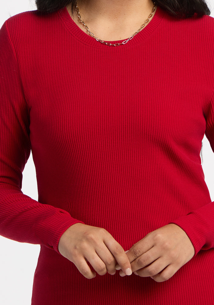 Woman wears Woolx Hadley Ribbed Crew in Maraschino Cherry with a gold chain necklace, hands clasped.