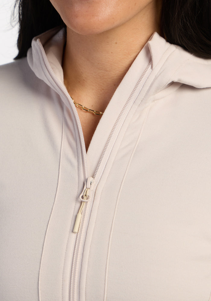 Close-up of a woman in the Woolx Zoey Zip Up Hoodie - Ecru, paired with a gold chain necklace.