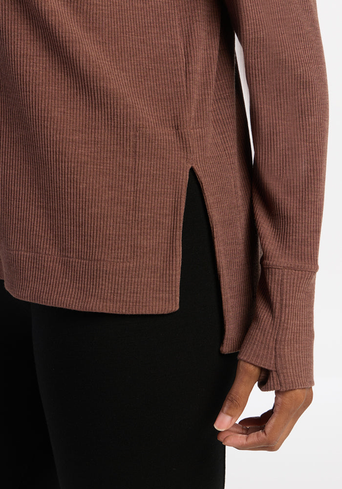 A person wears the Woolx Ainsley Sweater in Sable Heather with black pants, hand relaxed by their side.