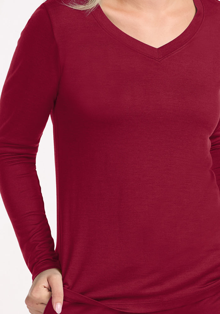 A person wearing a long-sleeved, beet-red Woolx Lily V Neck Lounge Top for sleepwear.