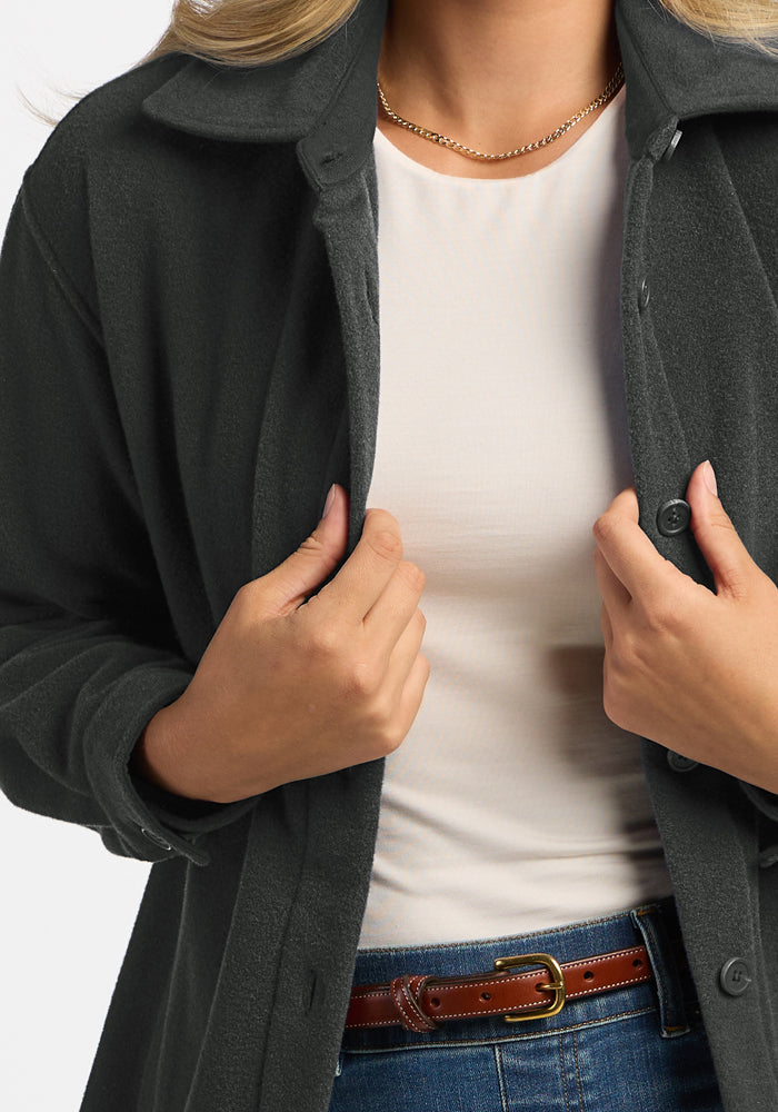 Woman wearing the Woolx Jovie Shacket in Volcanic Ash over a white shirt and blue jeans, holding it open with both hands.