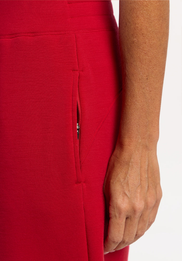 A hand rests beside a zippered pocket on Woolx Bree Lounge Pants - Maraschino Cherry, relaxed fit Merino wool.
