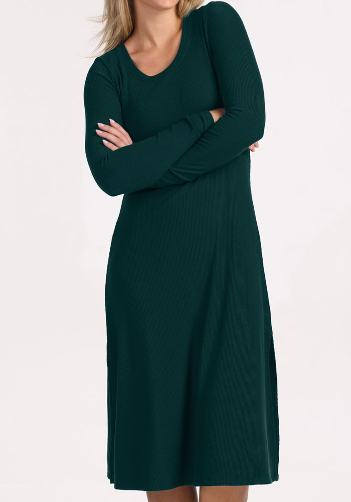 Woman in the Woolx Caroline Ribbed Twirl Dress - Deep Pine stands with arms crossed, dress pops against white.