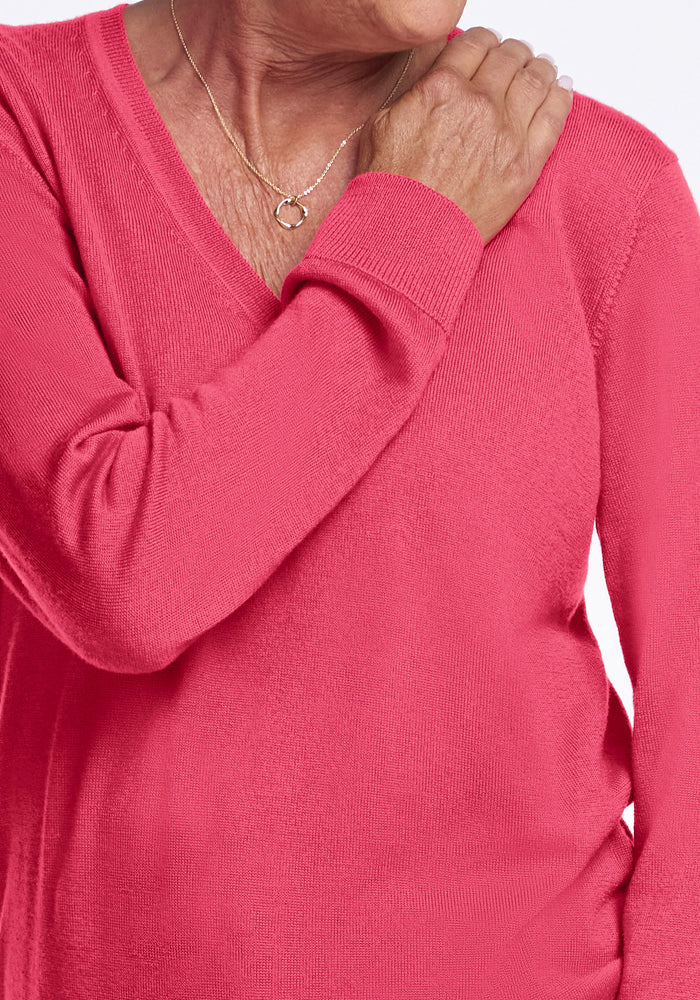Person in the Woolx Francesca Sweater in Vivid Rose rests their right hand on left shoulder, face partly out of frame.