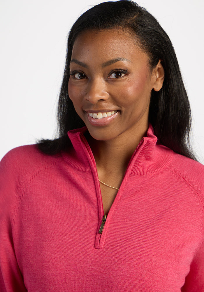 Smiling woman in Woolx Collins Half Zip Sweater - Vivid Rose, facing camera against a white background.