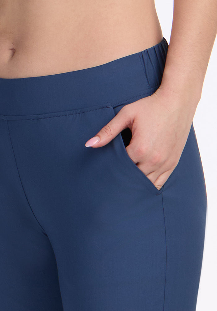 A person wears Woolx Nicole Crop Pants in Vintage Indigo, high-waisted merino wool trousers, with their right hand in the pocket; only the torso and upper legs are visible against a plain light background.