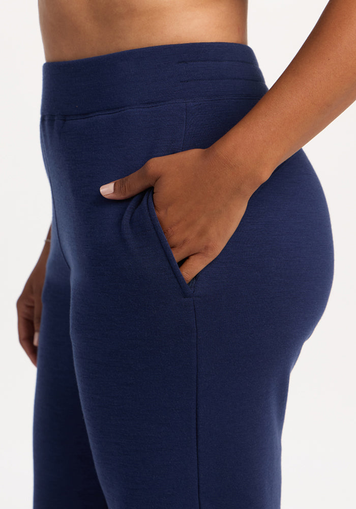 Person wearing Woolx Bree Lounge Pants in Ocean Cavern, hand in pocket, shown from the side against a plain background.