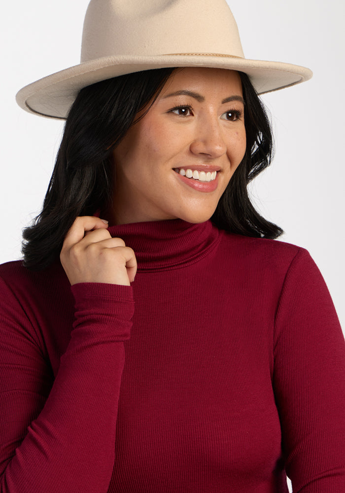 Woman in a Woolx Sage Ribbed Turtleneck in Beet Red smiles, looking to the side against a light background.