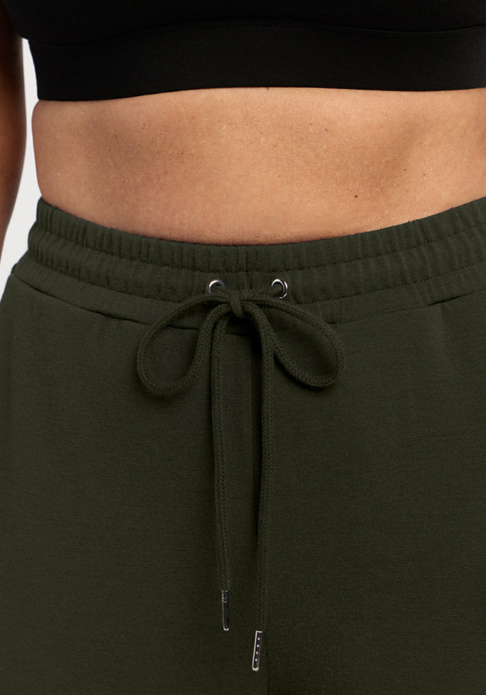 Close-up of a person in Woolx Eloise Wide Leg Pants - Duffel Bag and a black crop top, midriff showing.