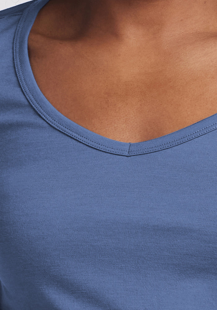 Close-up of a person wearing the Woolx Layla V Neck Top in Skyline, highlighting its smooth, odor-resistant fabric, fine stitching details, and the stylish V neckline.