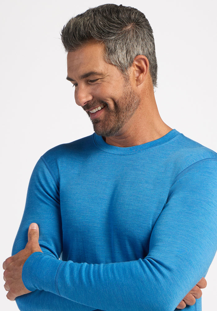 Smiling man in Woolx Explorer Base Layer - Blue Razz, neatly trimmed gray hair and beard, looks left.