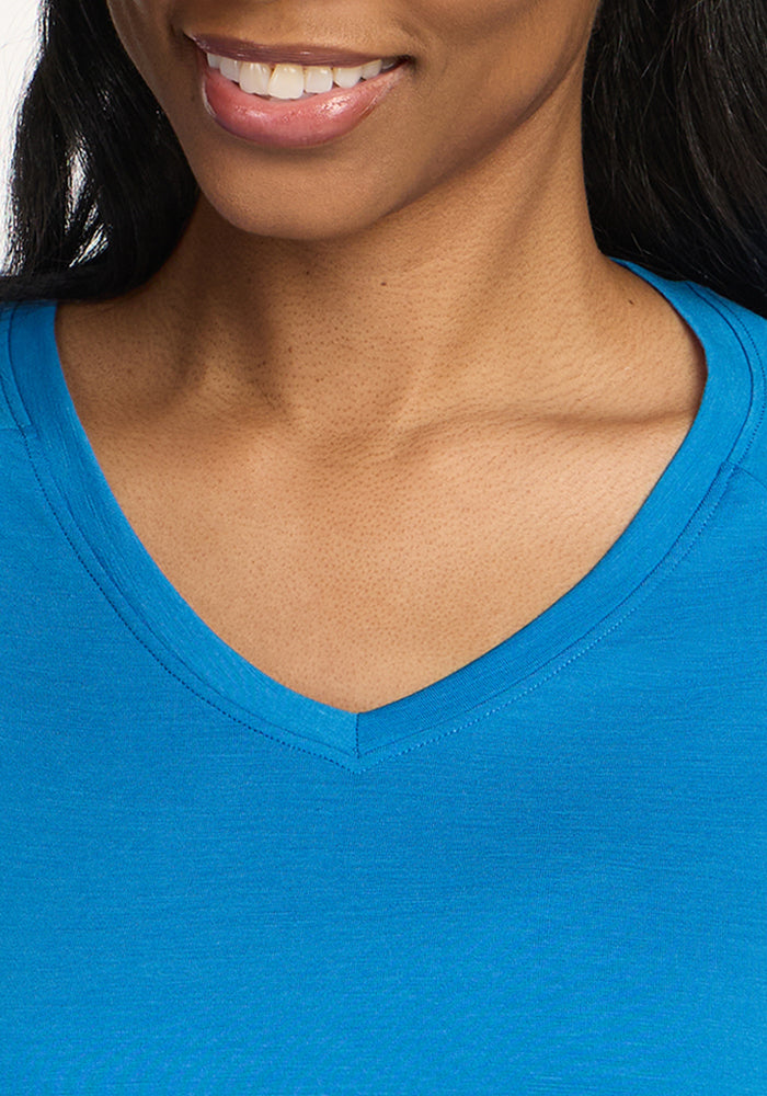 A close-up of a smiling woman wearing the Woolx Mia V Neck - Wave Rider. Only her mouth, part of her chin, neck, and upper chest are visible.