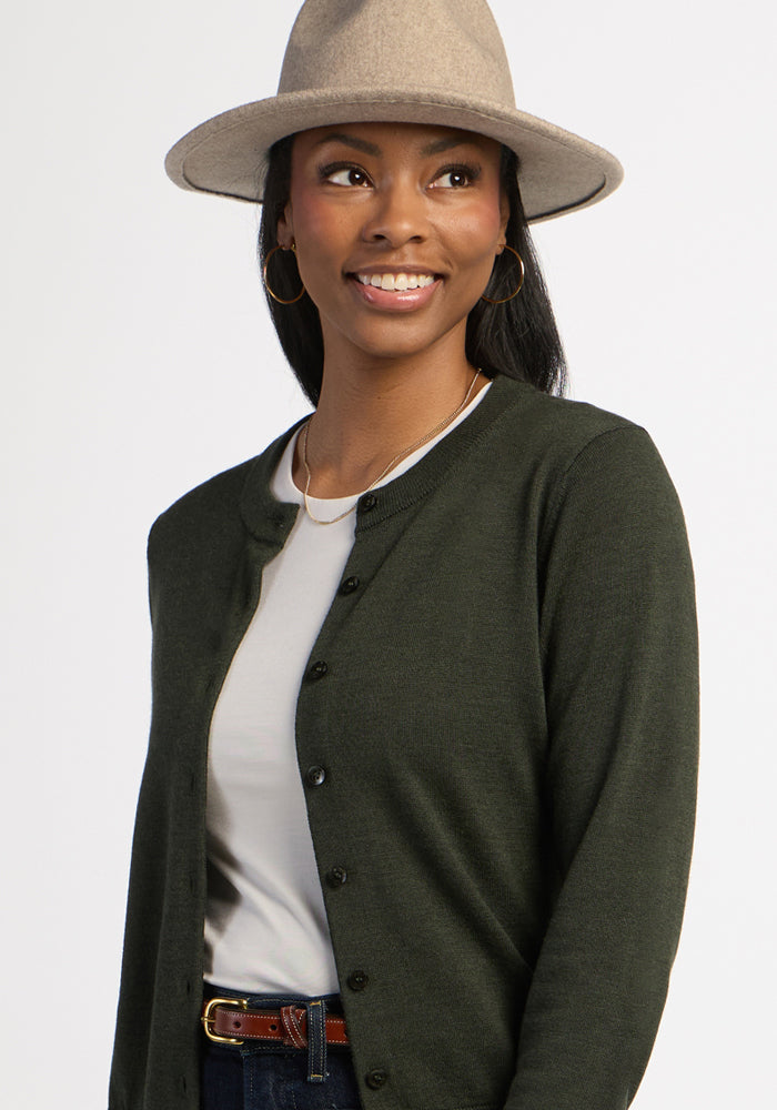 Woman in the Woolx Caitlin Sweater - Duffel Bag, smiling in a cozy look with a beige hat against a plain background.