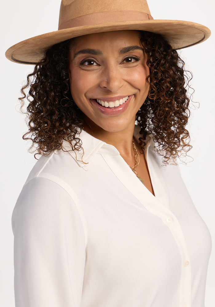 Woman with curly hair smiles in the Woolx Lorelai Button Up - Eggshell, loving its moisture-wicking merino wool comfort.