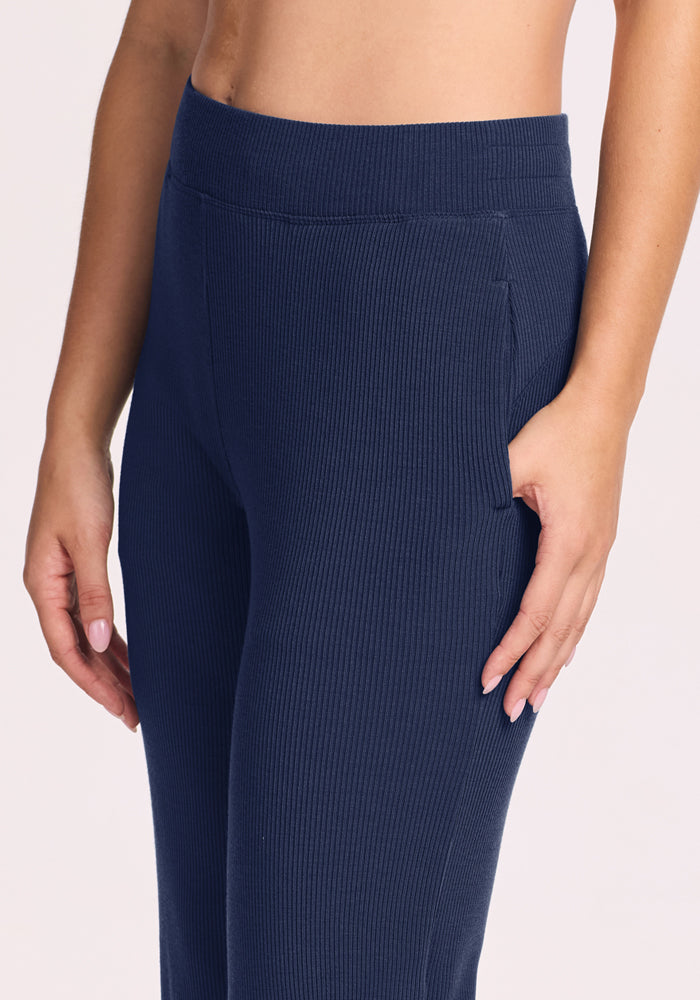 Someone in Woolx Luca Petite Pants - Ocean Cavern, high-waisted and ribbed, shown waist to upper thigh with a pocket.